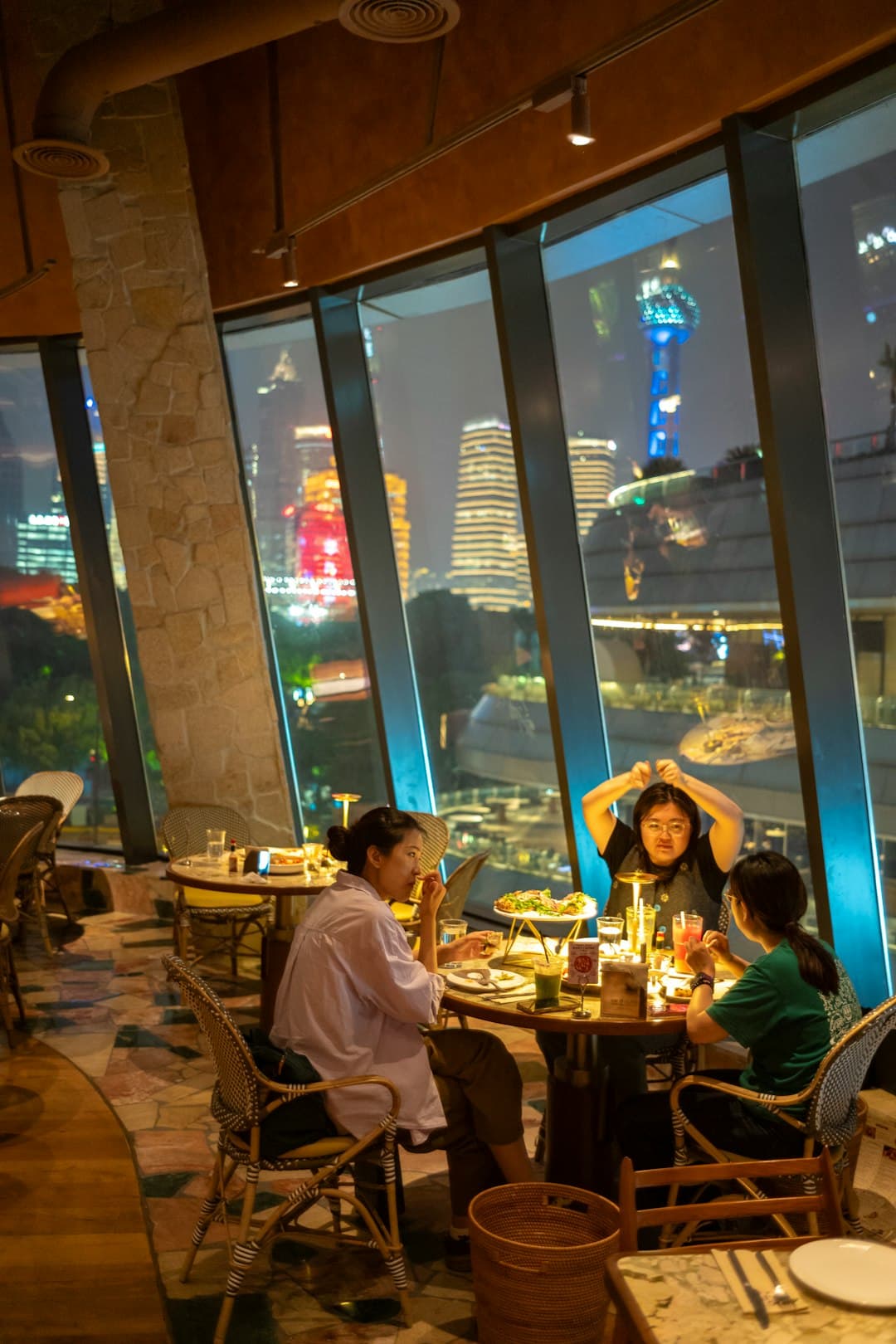 Three people eating together at a window table late in the evening.